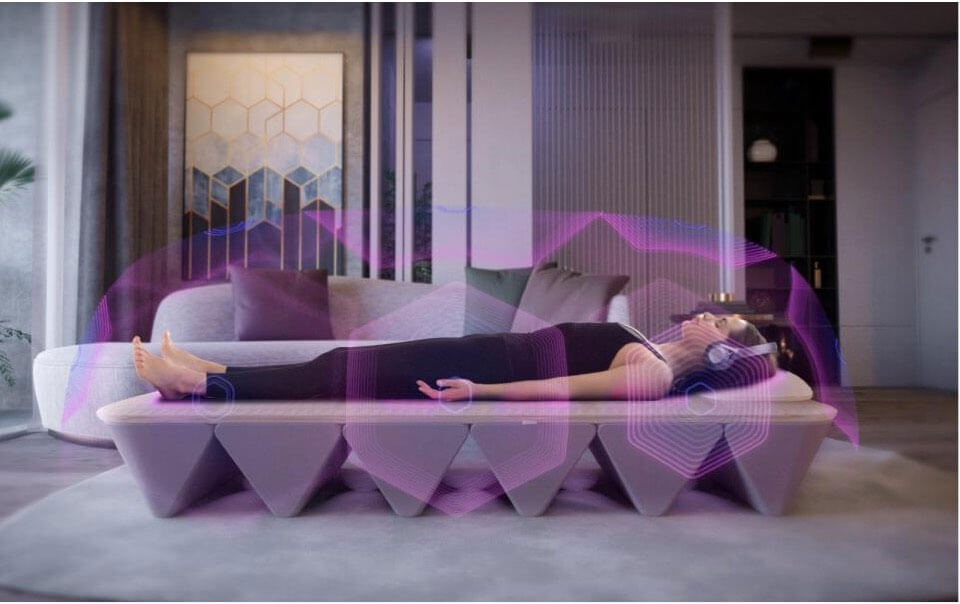 A person relaxing on the SoundBed with headphones on, visualized vibroacoustic sound waves moving through their body